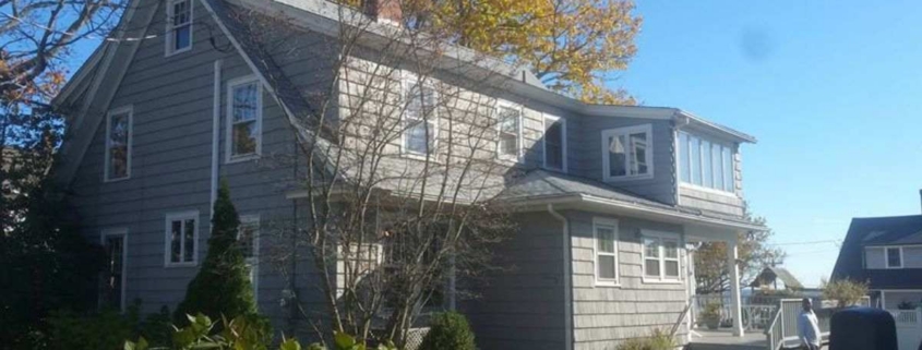 Gray home with mixed siding and autumn background.