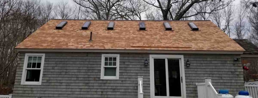 Gray cottage with cedar shake roof and skylights.