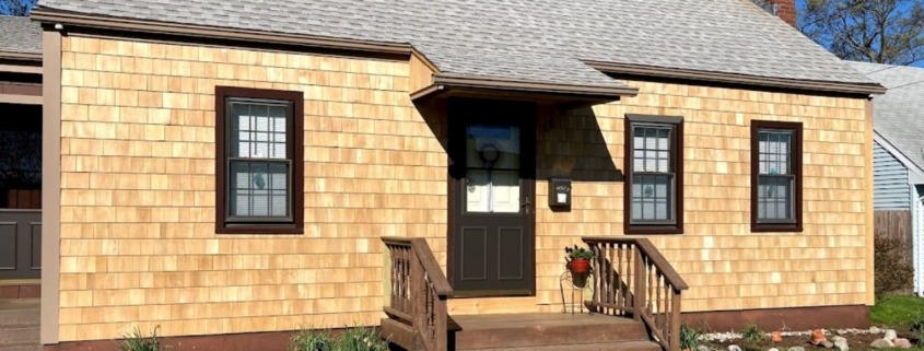 A charming house with brown siding and a front porch, situated in Milford.