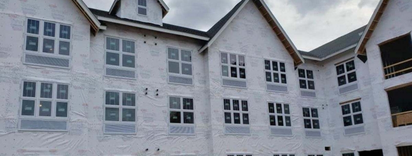 Building under construction with white wrap and windows.