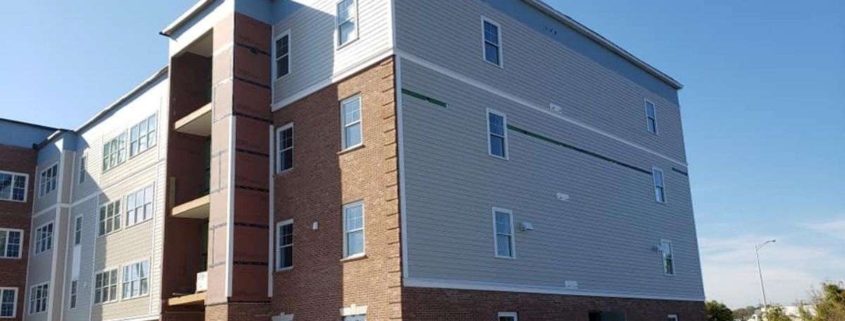 Multi-story building under construction with brick and siding.