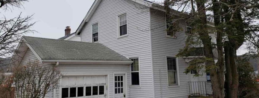 White house with garage and snow-covered yard.