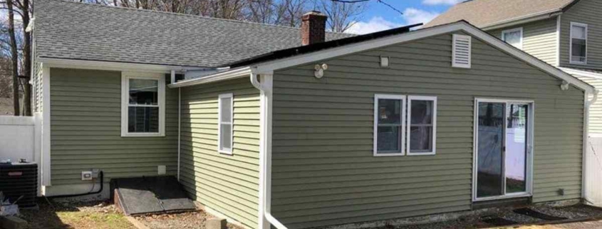Ranch house with green lap siding, white trim, sliding door.