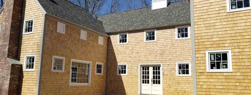 Large home with cedar shingles, cupola, and brick chimney.