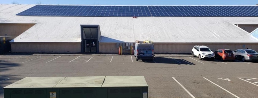 A sizable structure in Woodbridge equipped with solar panels on the rooftop for sustainable energy use.