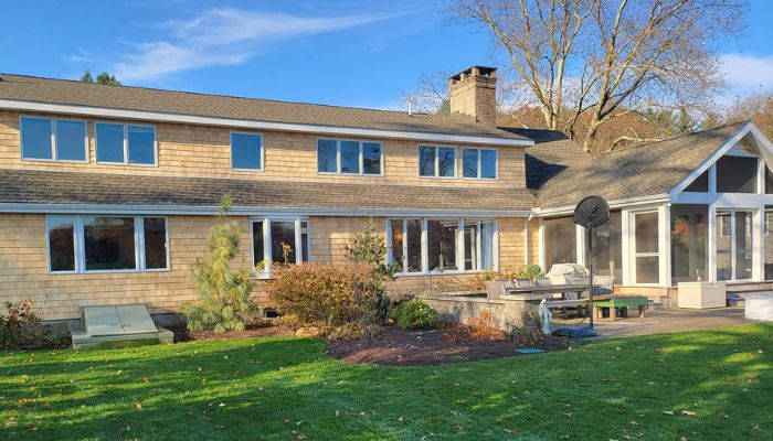 A large two-story house with a shingled roof and spacious backyard.