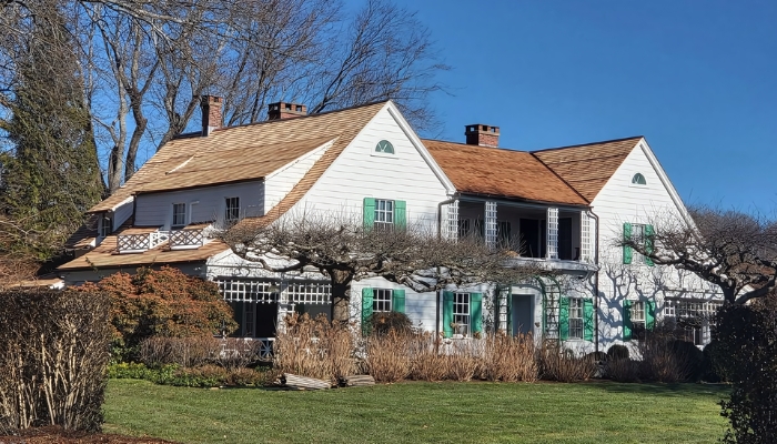 A prominent white house with green shutters, showcasing a blend of elegance and charm in a serene environment.