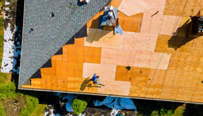 Aerial view of a roof replacement in progress, highlighting the installation of new shingles and plywood decking—an essential process for understanding when to replace your roof in Connecticut.