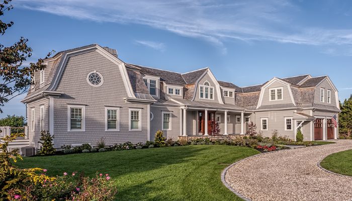 A large home in Connecticut with a driveway, illustrating the topic of roof repair versus replacement.