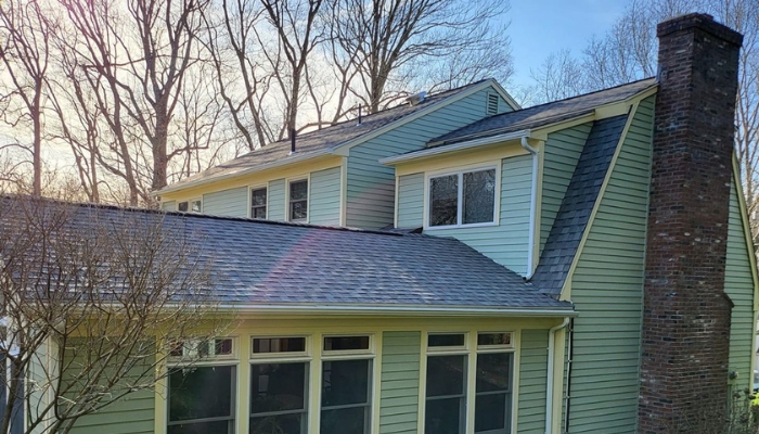 A house with a asphalt roof and chimney, illustrating the discussion on roof age and repair versus replacement in Connecticut.