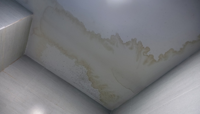 A bathroom with a stained ceiling and light fixture, suggesting issues that may require roof repair or replacement in Connecticut.