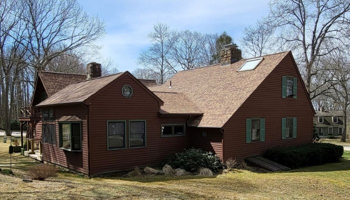 A red house with a brown roof and green trim, highlighting K.P. LaMarco Construction's roofing materials recommendations.