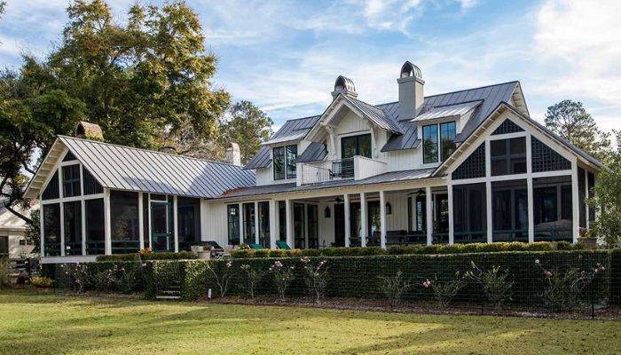 A large white house with black trim features a spacious porch, showcasing a classic architectural style.