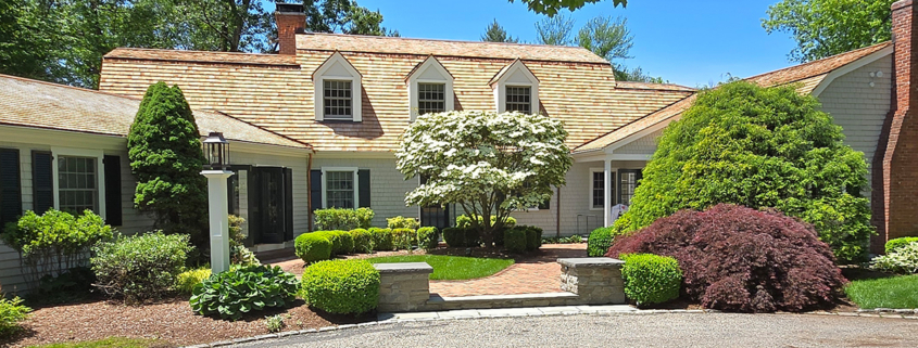 A well-maintained home featuring a driveway, landscaped yard, and a sturdy roof.