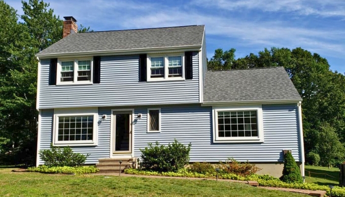A blue house with contrasting white trim and black shutters, representing the style and value of Hardie Plank siding.
