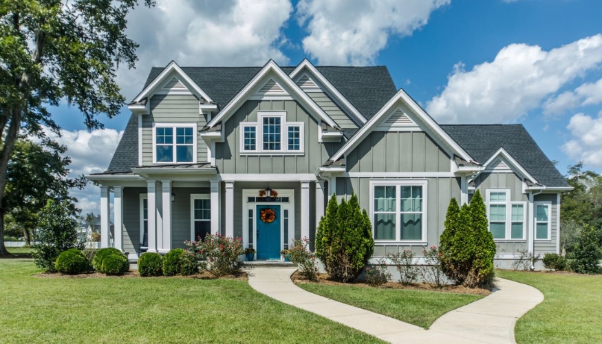 A charming home featuring a blue door and white trim, highlighting its energy-efficient new siding.