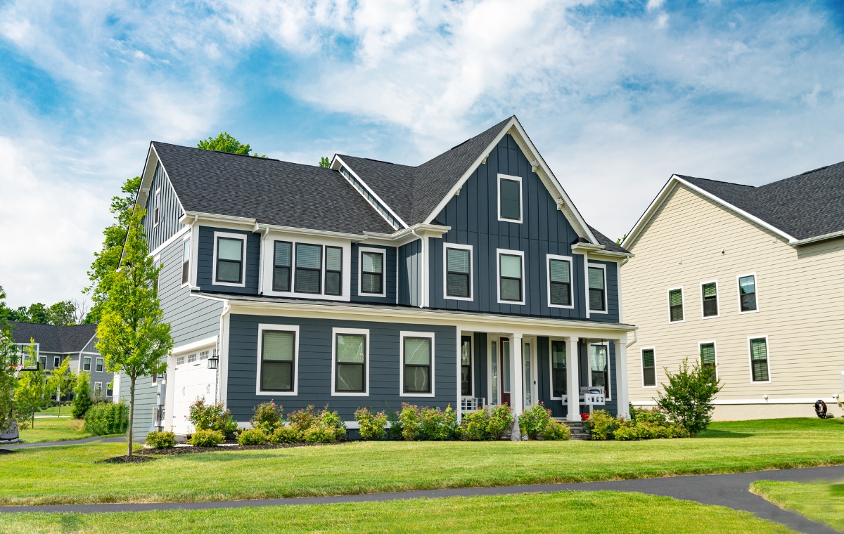 A prominent house featuring a driveway and a lush lawn, highlighting recent siding installation.