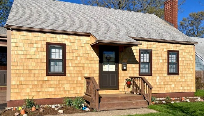 A small residence with brown siding and a brown door, representing suitable wood siding for homes in New England.