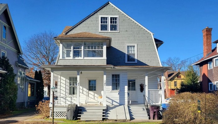 A two-story house with a front porch, showcasing ideal siding options for New England's climate and budget considerations.