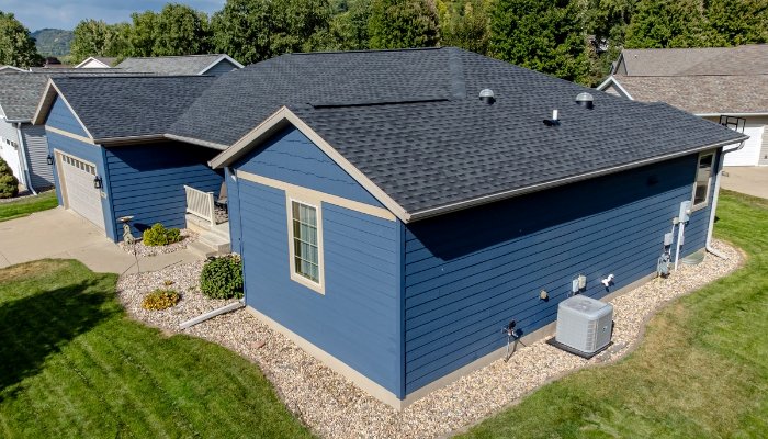 A blue house with a garage and driveway, showcasing fiber cement siding suitable for New England climates.
