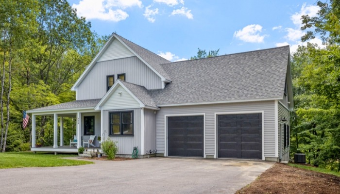 A home featuring a garage and driveway, showcasing vinyl siding suitable for New England climates.