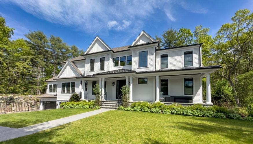 A spacious white house with lush green grass and trees, highlighting the impact of siding on curb appeal and ROI.