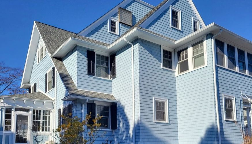A blue house with white trim and shutters, serving as a visual example in discussions about new siding cost factors.