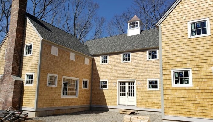 A house with a chimney, adorned with wooden siding made of cedar shakes, emphasizing natural aesthetics.