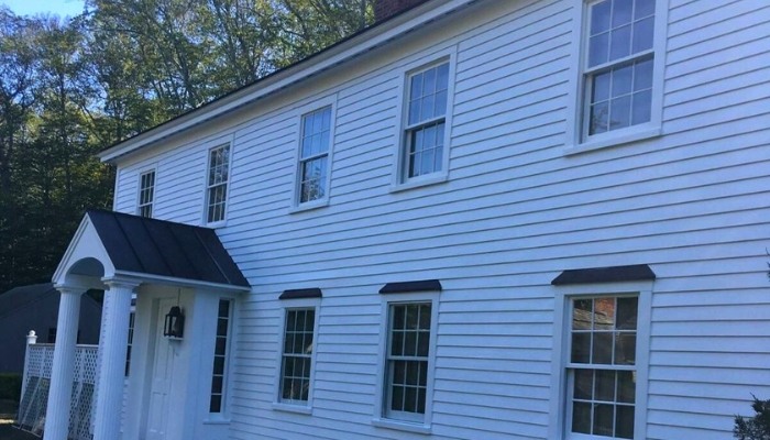 A white clapboard house featuring black trim and windows, showcasing a classic architectural style.