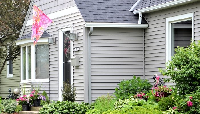 A house with vinyl siding featuring a flag displayed on the front porch, showcasing a welcoming exterior.
