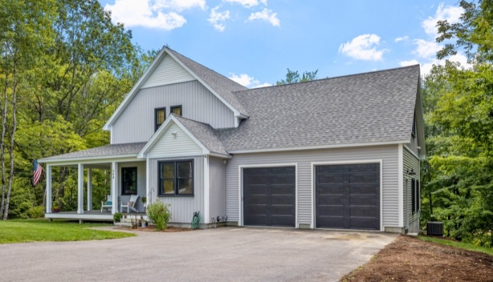 A home featuring a garage and driveway, showcasing vinyl siding, showcasing the types of siding Connecticut.