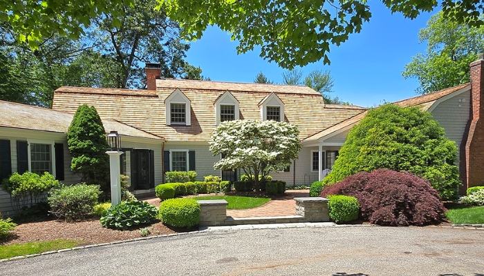 A home featuring a driveway and trees in the front yard, highlighting the benefits of cedar siding's customizability and versatility.