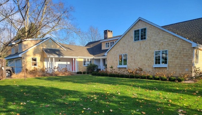 A spacious home with a large yard and driveway, showcasing eco-friendly cedar siding for sustainable living.