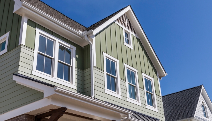 A house featuring green composite siding with white trim, highlighting its minimal maintenance and color stability benefits.