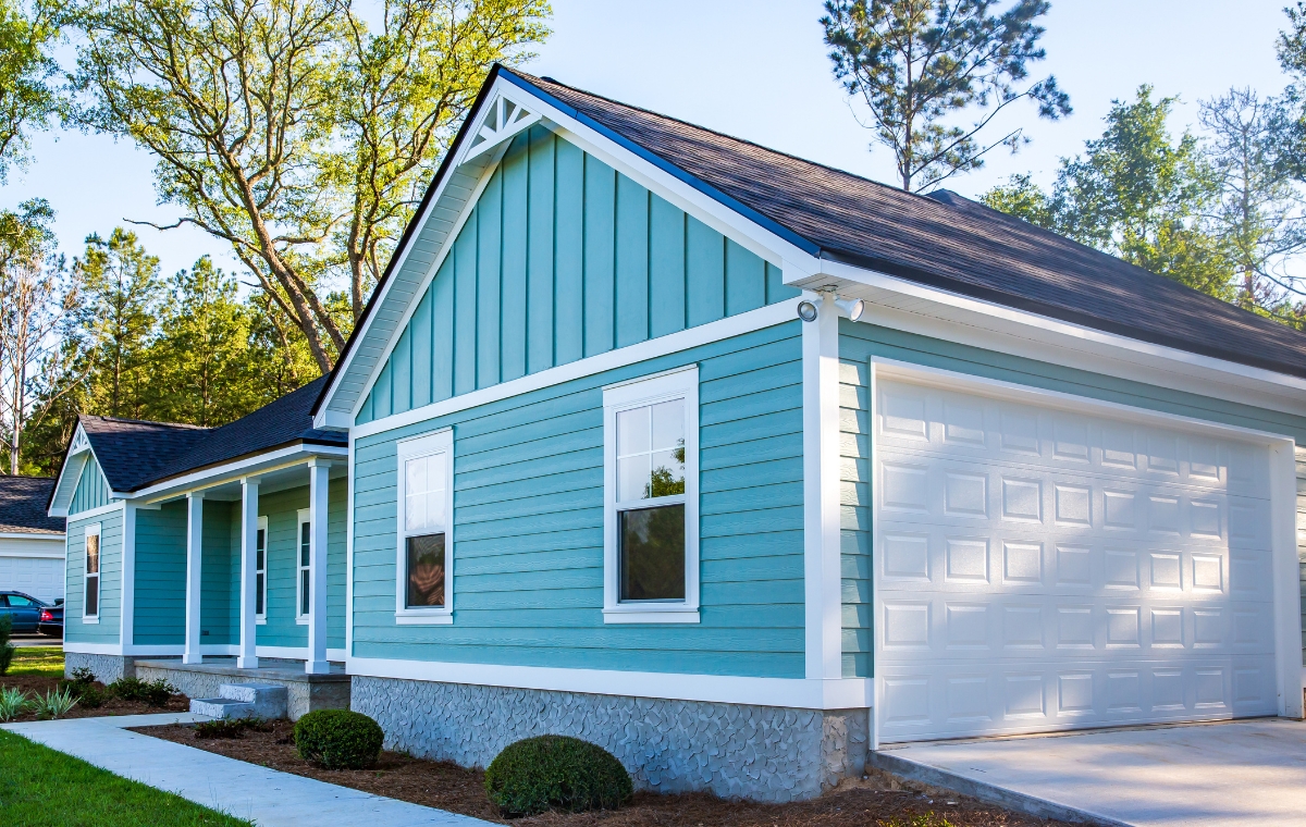 A blue house featuring white trim and a garage, representing a composite siding project in Branford, CT.