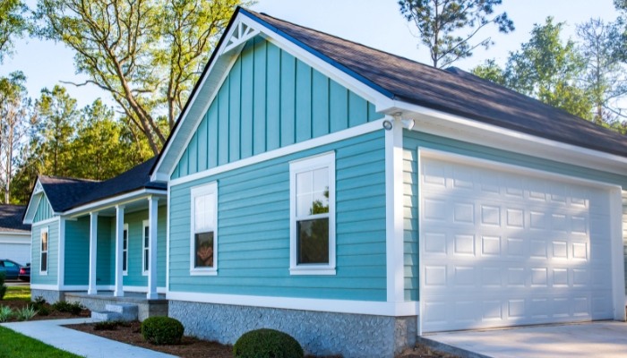 A blue house featuring white trim and a garage, highlighting the advantages of composite PVC siding.