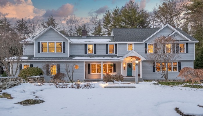 A snow-covered home with a clear driveway, illustrating the benefits of composite siding in winter weather conditions.