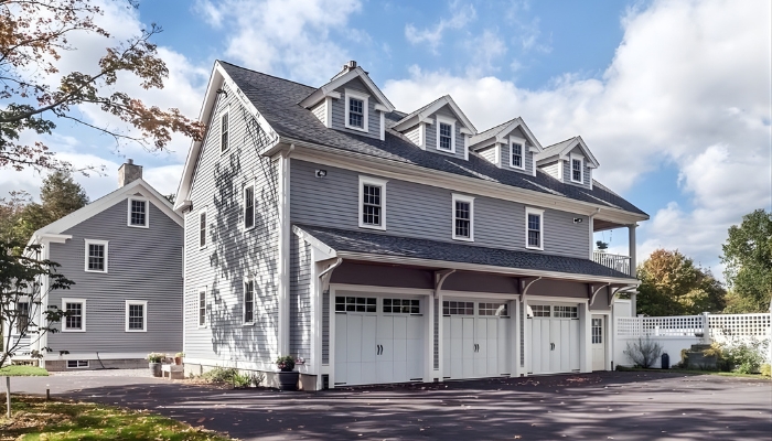 A gray house with three garages and a driveway, representing ideal siding options for enhancing home aesthetics.