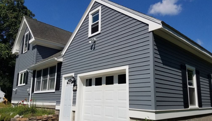 A gray house with a garage and a white door, showcasing popular siding options for enhancing home aesthetics.