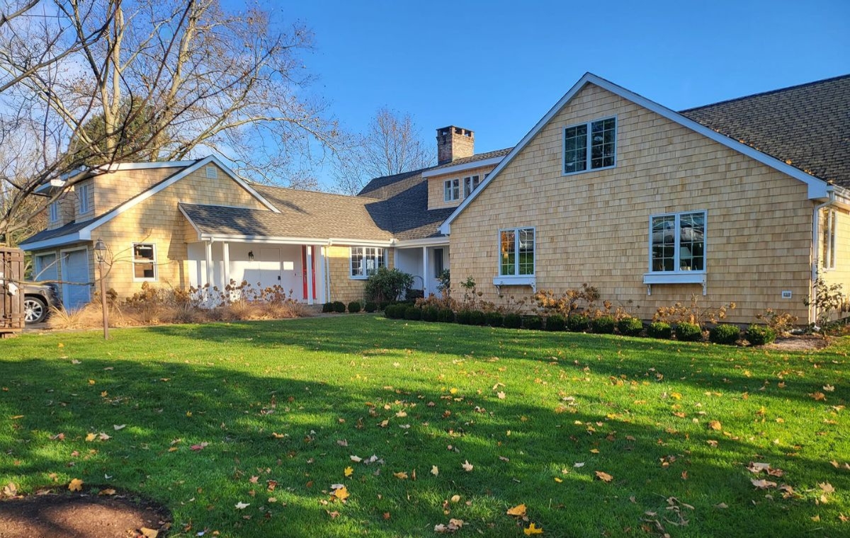 A large home with cedar siding, featuring an expansive yard and driveway, located in Essex, CT.