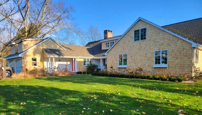 A residence with a large yard and driveway, illustrating the benefits of choosing cedar siding instead of composite materials.