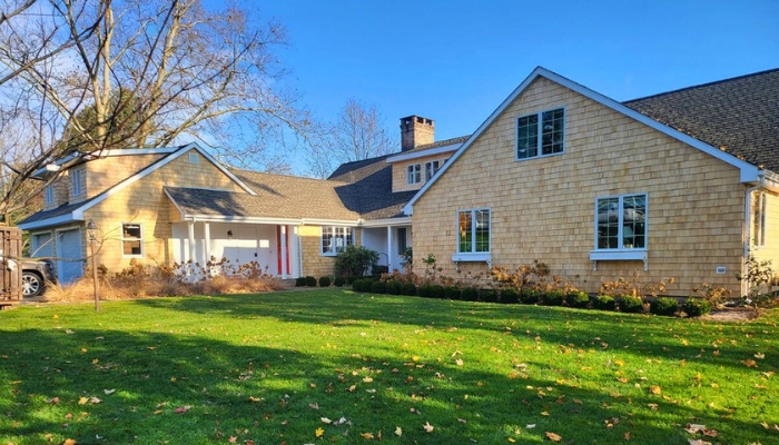 A residence with a large yard and driveway, illustrating the benefits of choosing cedar siding instead of composite materials.