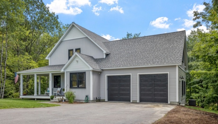 A gray house featuring a garage and driveway, illustrating the advantages of composite siding over cedar siding.