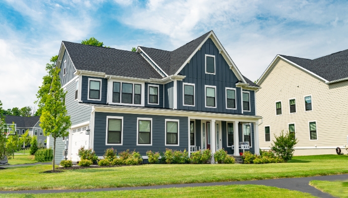 A house featuring gray siding with white trim, illustrating the aesthetic comparison between cedar and composite siding.