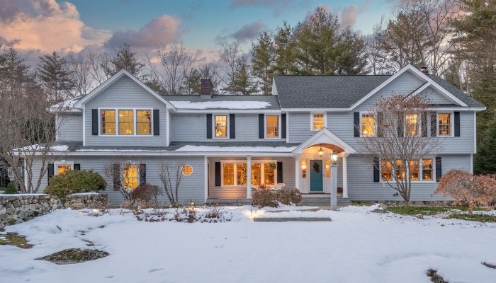 A house surrounded by snow, featuring a driveway, highlighting the impact of climate on siding choices.