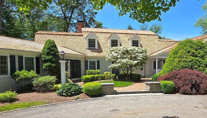 A home with a driveway and trees in the front yard, illustrating durability and maintenance of cedar vs. composite siding.