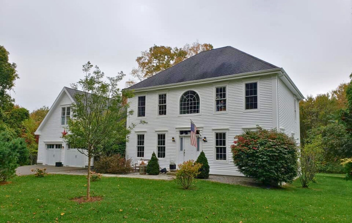 A large white house with a spacious yard, representing a siding company in Guilford, CT.