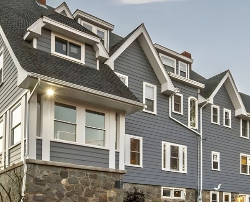 Three-story home with blue-gray siding and stone foundation