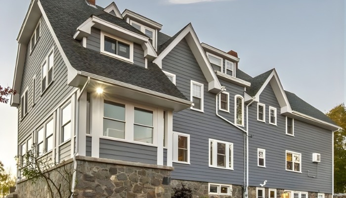 Three-story home with blue-gray siding and stone foundation
