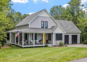 A residential house with a spacious porch and a flag at the entrance, indicating the presence of a roofing contractor.